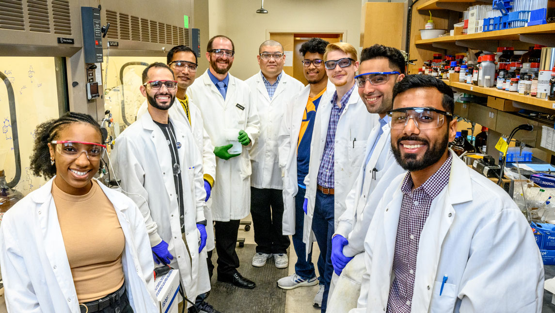 nine scientists in lab coats in a lab