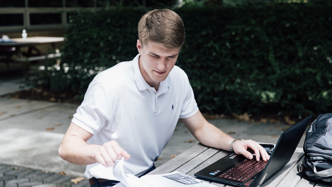 UNCG Student studying on their computer outside.