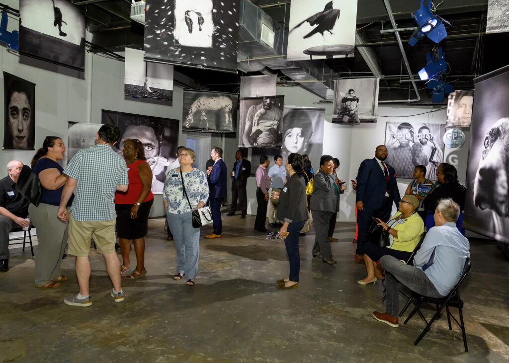 People mingle in an art gallery with black and white photos on display.