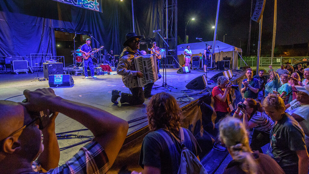 A man places the accordion onstage while a crowd watches.