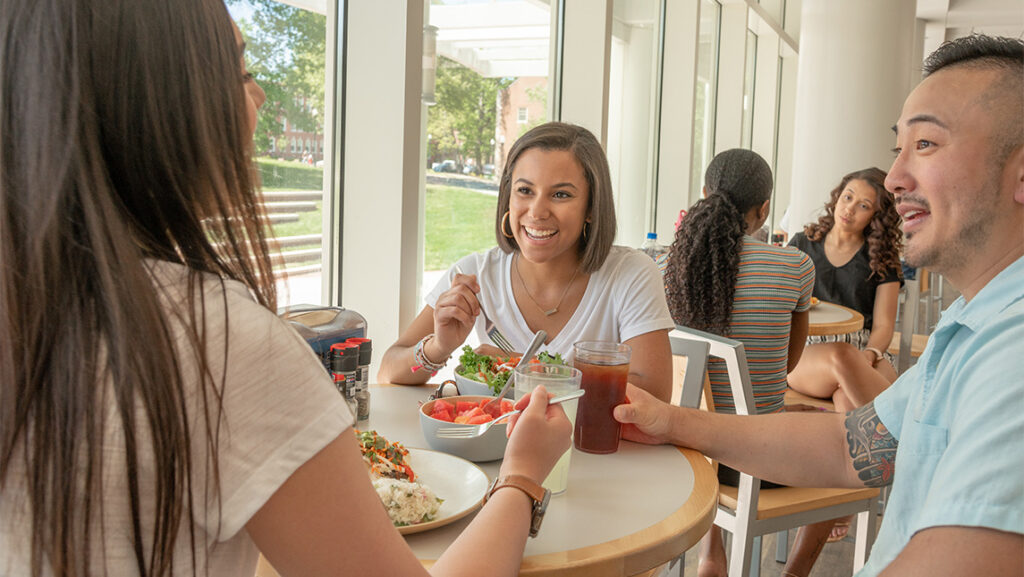 Students sit at a table eating food in UNCG's Fountain View Dining Hall.