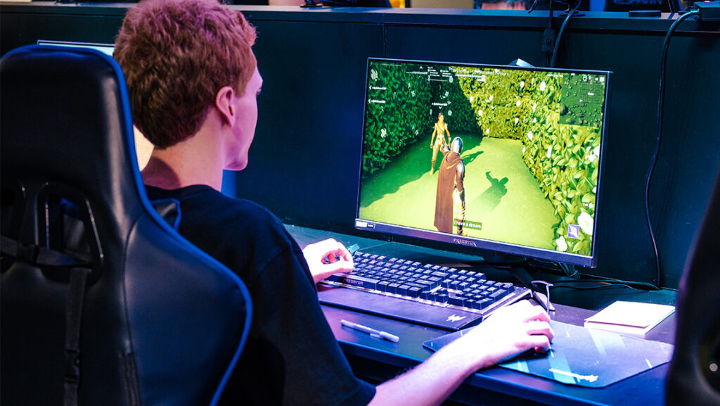 A man plays games on a PC in UNCG's esports arena.