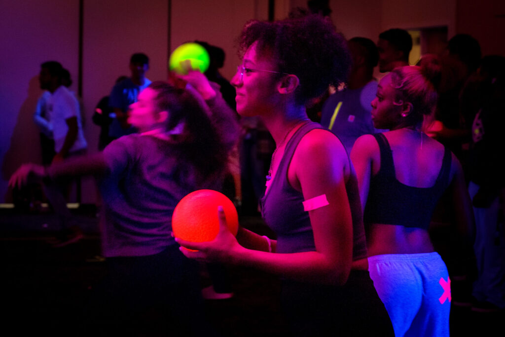 Students playing dodgeball glow in black light.