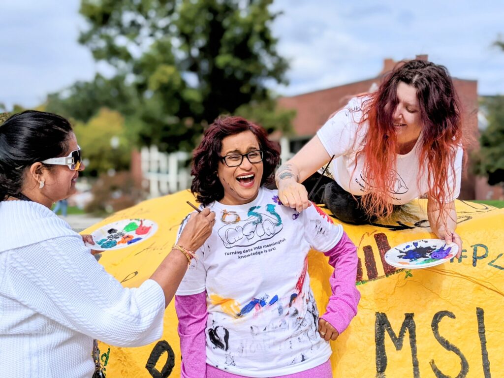 UNCG faculty member Dr. Prashanti Manda wears a t-shirt being painted by students.