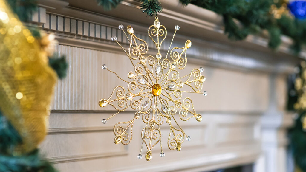 A snowflake ornament hangs from a fireplace mantle in the UNCG Alumni House.