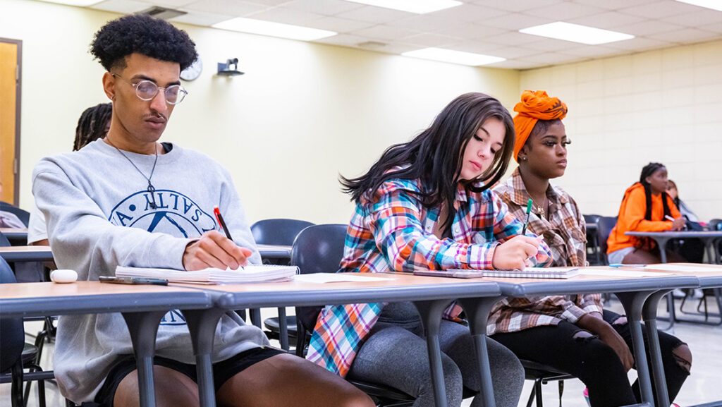 Three UNCG students work together at a classroom table.