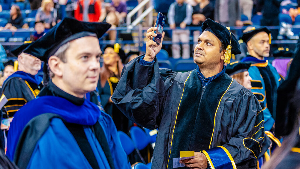 A doctoral student takes a photo during the UNCG graduate ceremony.