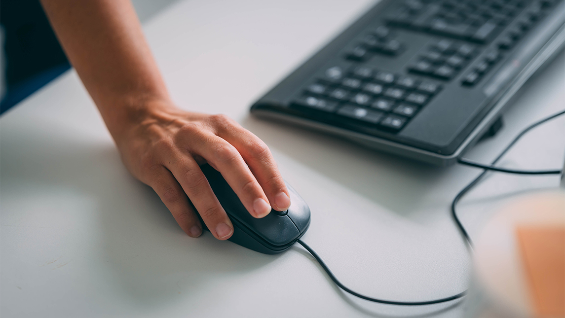 A close-up image of a person's hand on a computer mouse.