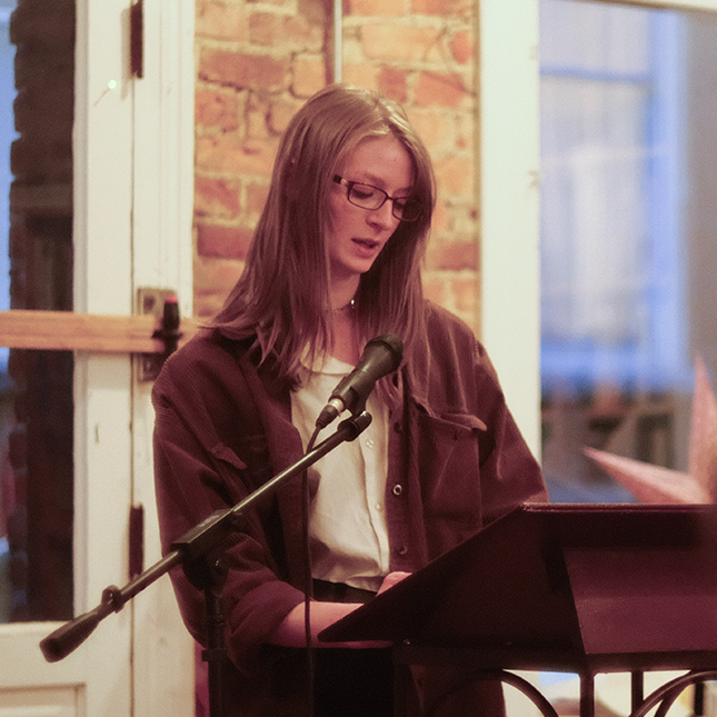 Student stands at a poem and reads to a group at Scuppernong Books.