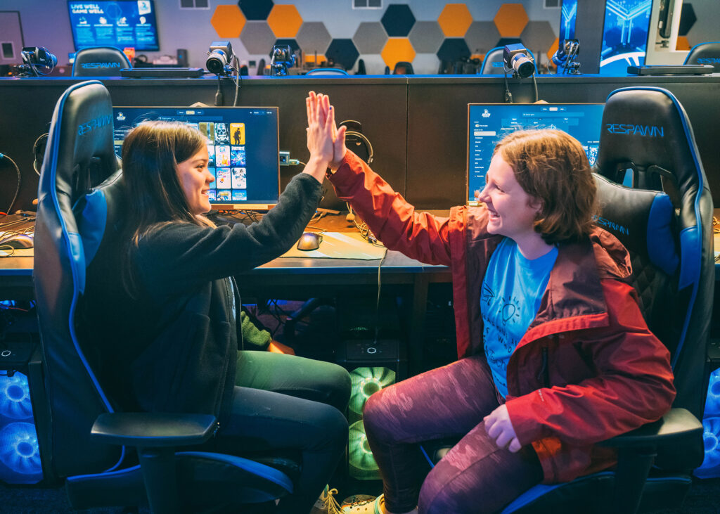 Two middle school girls give each other a high five in the esports arena.