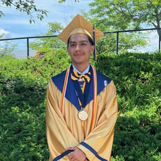 Graduate poses in yellow cap and gown with cords and medals.