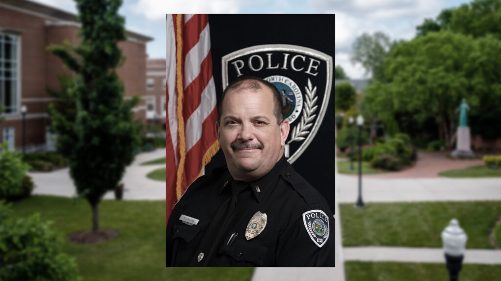Headshot of UNCG Police Captain DeDona against a landscape image of the campus.