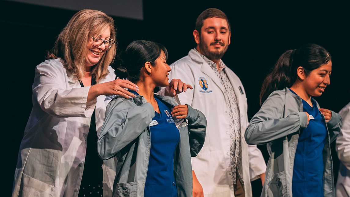 UNCG nursing students receive their grey coats from faculty.
