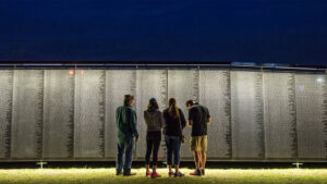 A family stands in front of a replica of the Vietnam War Memorial.