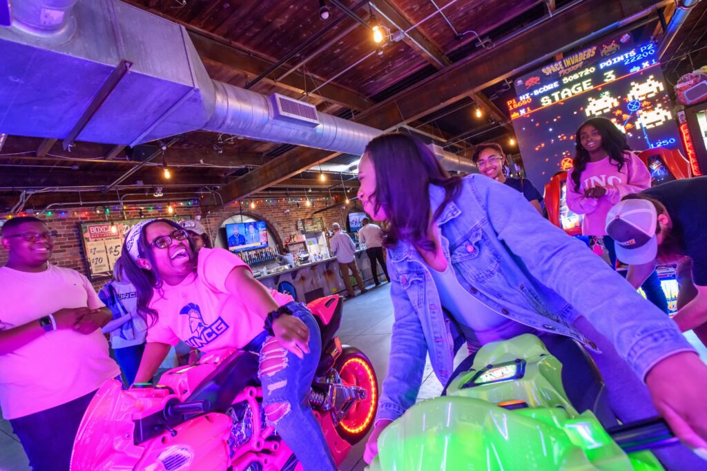 UNCG students ride the motorcycle simulator games in an arcade.