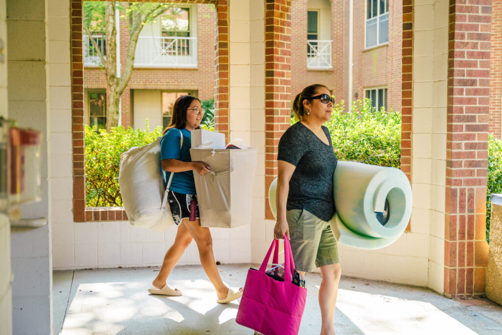 Student and mother bring belongings into residence hall during move-in.
