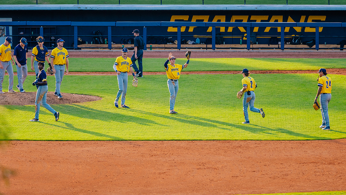 UNCG baseball players run onto the field.