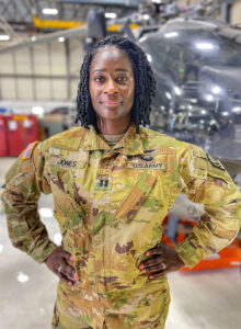 Captain Lindsey Jefferies Jones in fatigues and in front of a helicopter in its hanger.