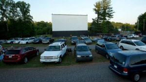 Cars parked around an outdoor movie screen.
