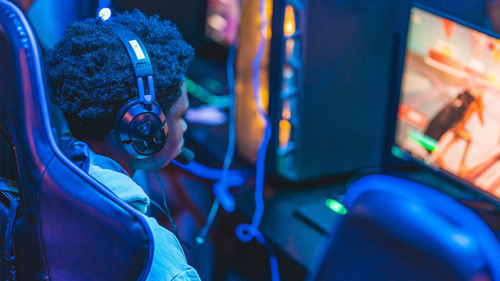 A boy with headphones looks at his video game screen at the UNCG Esports Arena.