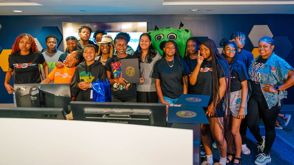 A group of middle and high school students take a group photo at the UNCG Esports Arena.