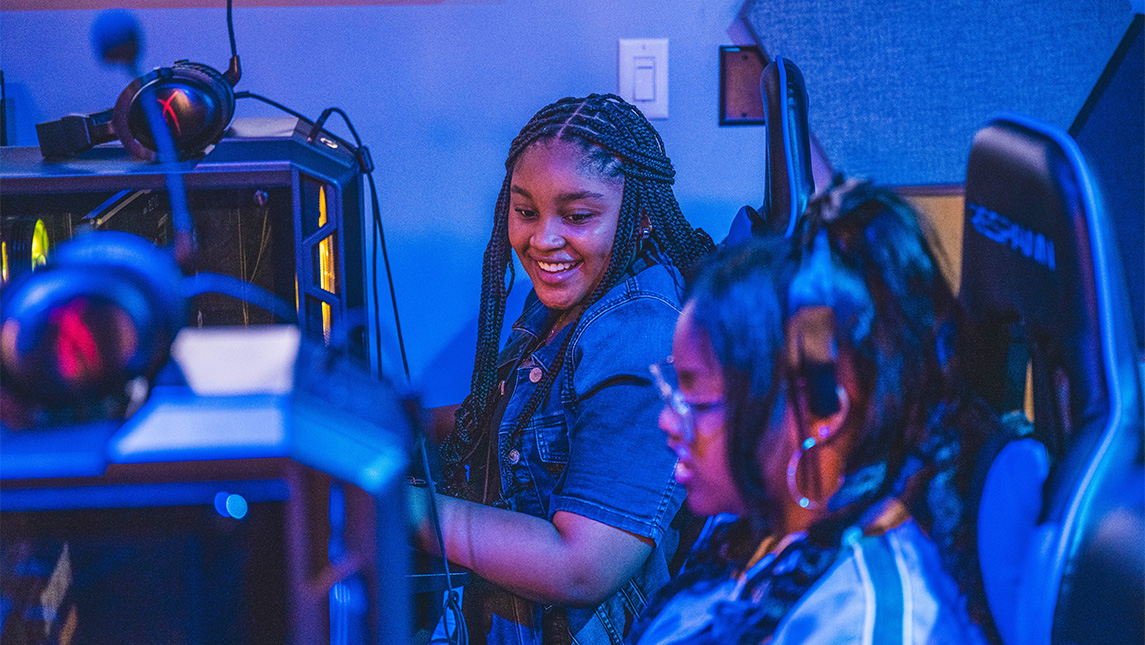Two girls laugh while playing games at the UNCG Esports Arena.