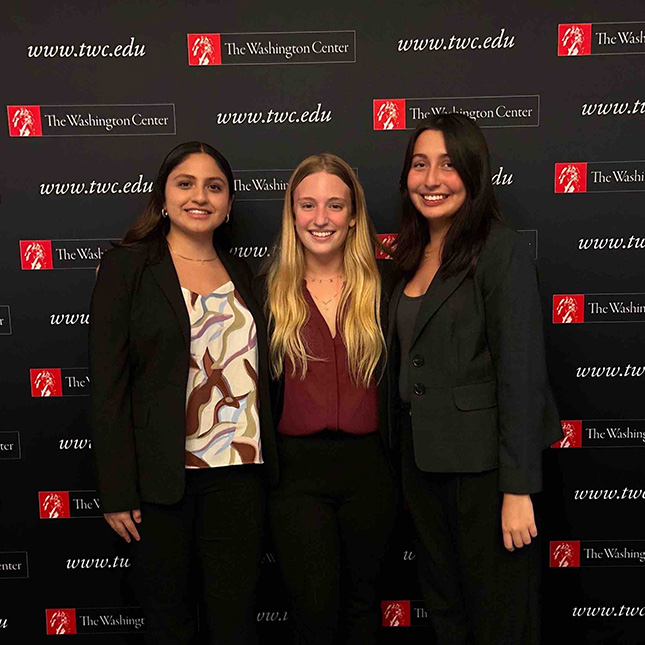 Three young women pose in front of a screen with The Washington Center logos.