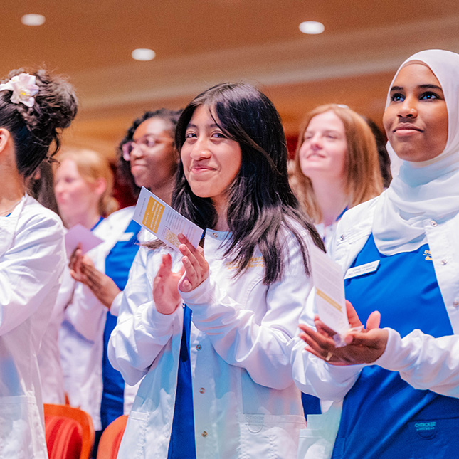 Nursing students stand and clap at their jacket ceremony.