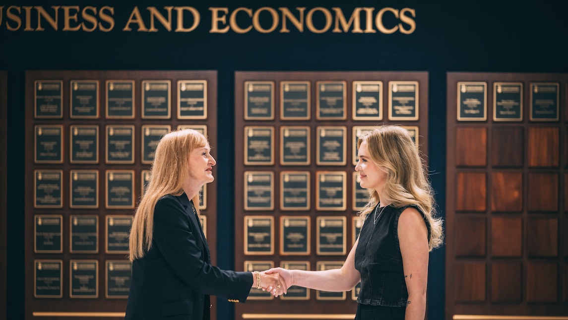 Leah Zubke, Bryan School alum and her professor shake hands.