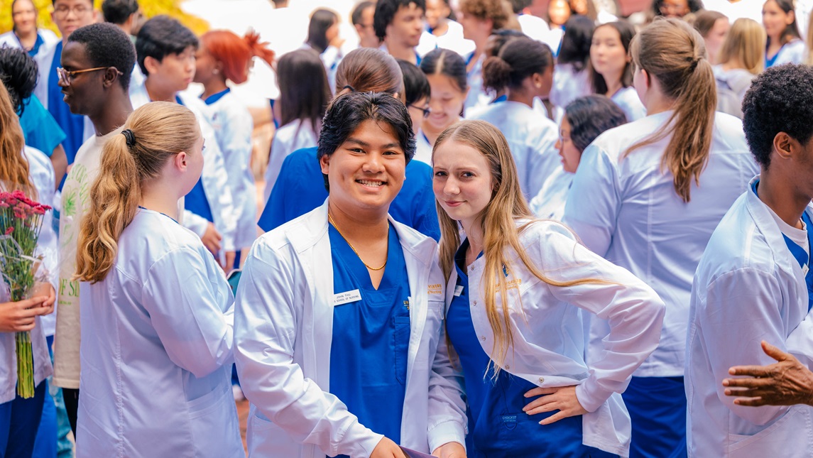 Two UNCG nursing students looking at the camera with other students in background