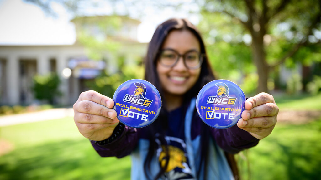 a young women holds up voting buttons