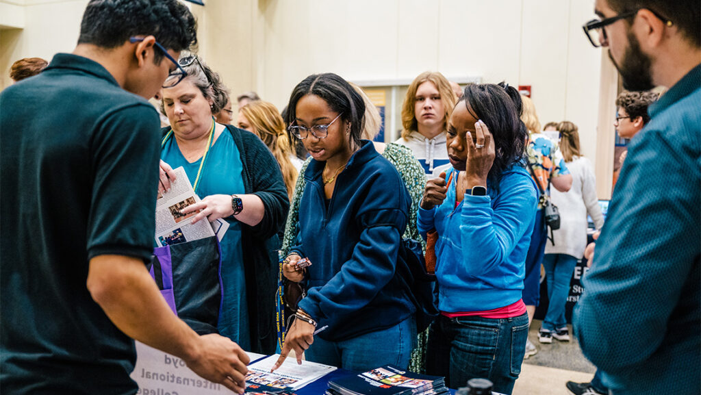 Families look at UNCG booklets on a table.