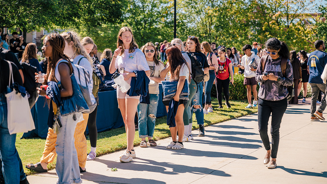 Students walk along a sidewalk at UNCG.