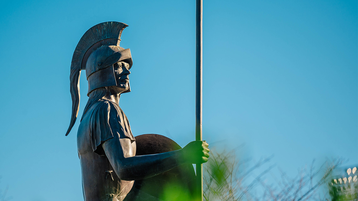 The Spartan statue stands over UNCG campus on a sunny day.