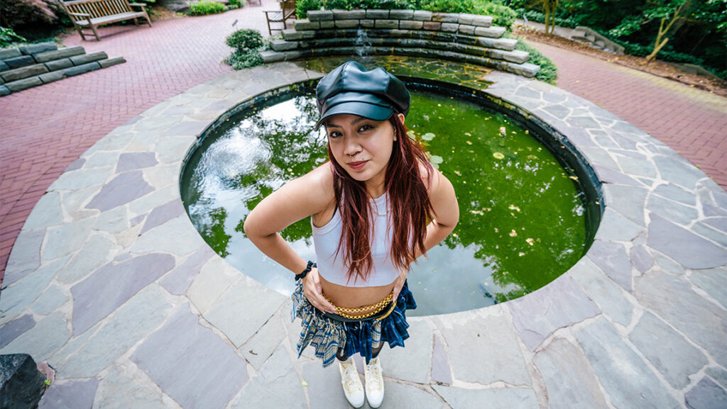 A student strikes a pose in front of the pond at the UNCG Music Building.