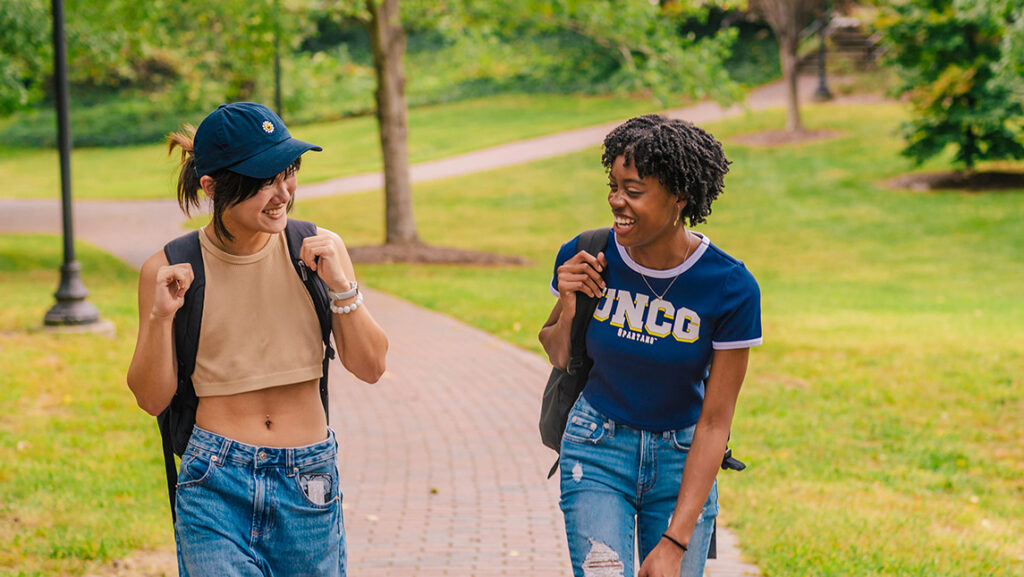 Students laugh as they walk through UNCG's Foust Park.