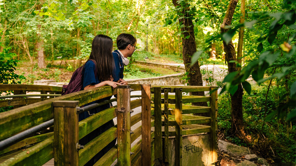 Two UNCG students look over the bridge to the Music Building.