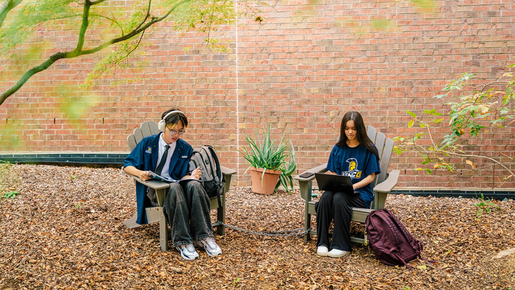 Students sit in chairs and work on homework.