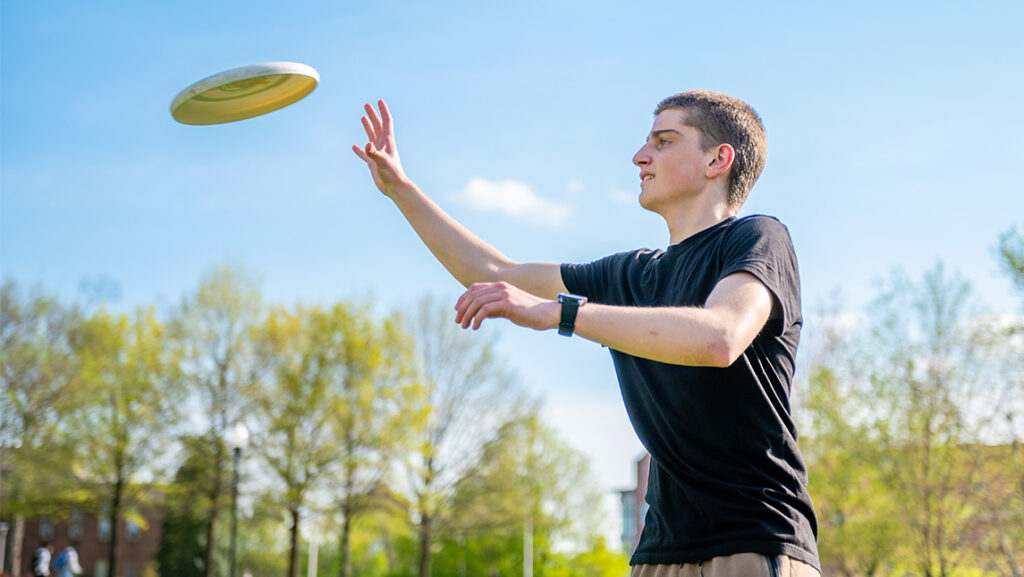 A UNCG student catches a frisbee outside.