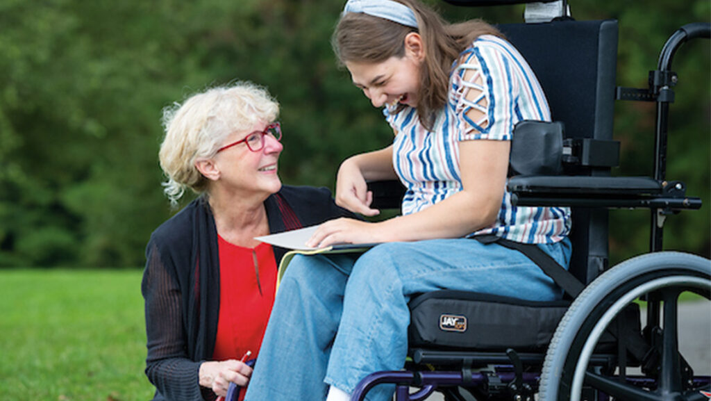 UNCG Professor Diane Ryndak talks to a girl in a wheelchair.