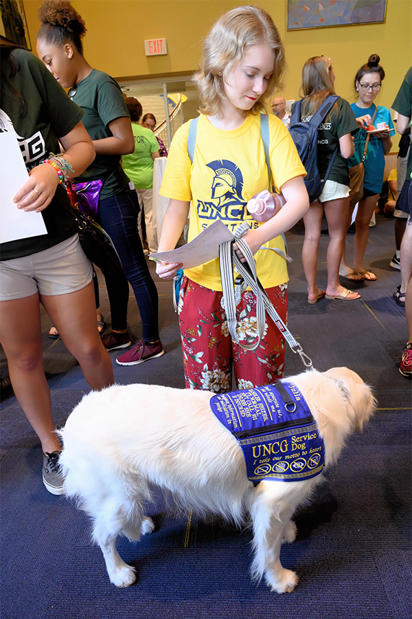 A student walks through UNCG with a service dog.