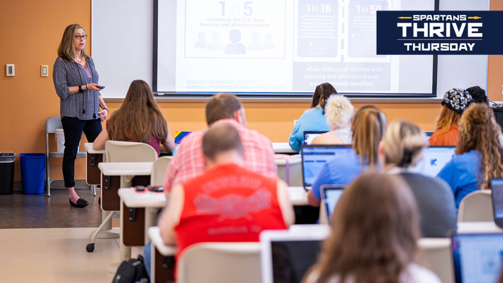 Students watch what is on a projection screen in a UNCG classroom.