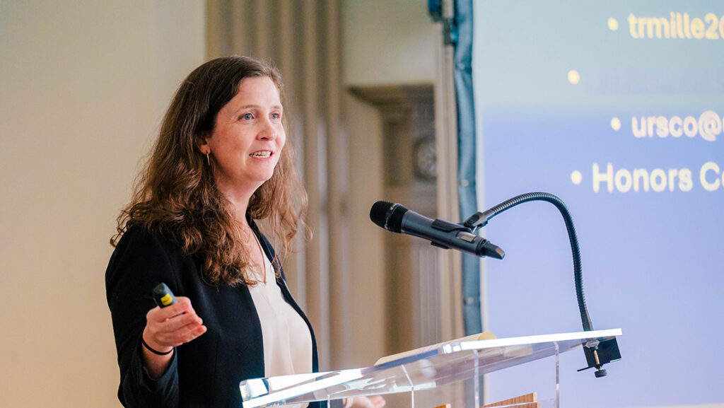 UNCG's Dr. Kimberly Petersen gives welcoming remarks at a podium.