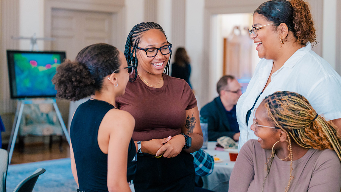 A group of students chat in the UNCG Alumni House.