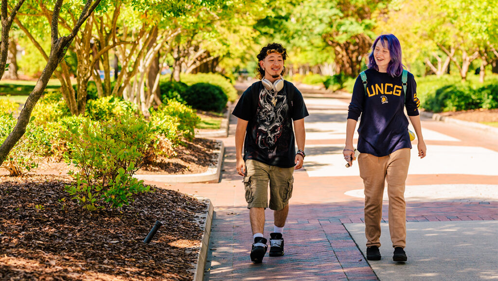 Two UNCG students chat as they walk down College Avenue.