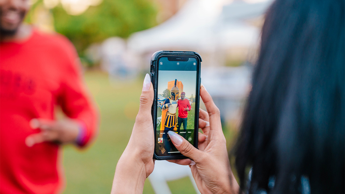 Close-up on a camera's preview screen taking a picture of a UNCG student with the Spiro mascot.