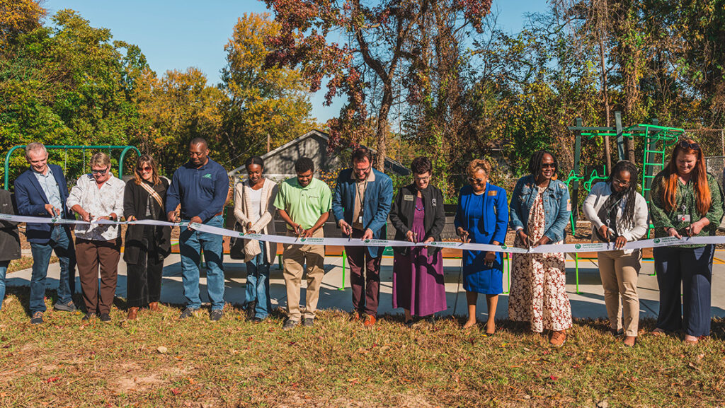 Group of people cut a ribbon in a city park.