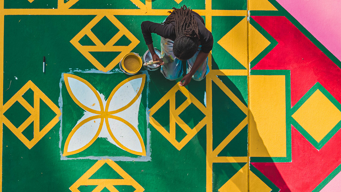 Arial view of a colorfully painted sidewalk with an artist working on it.