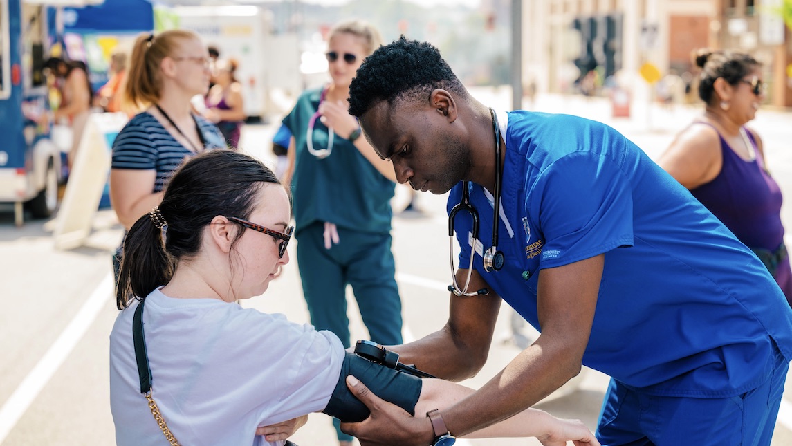 UNCG Nursing student taking someones blood pressure.