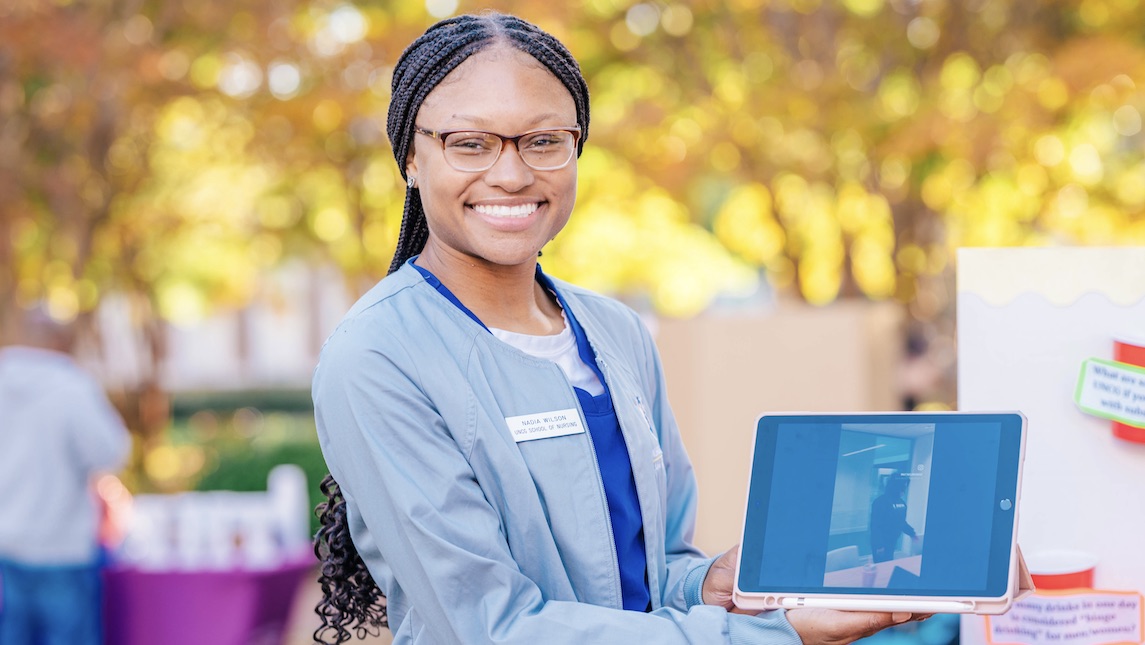 UNCG nursing student poses with an iPad during a festival.